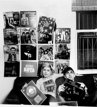 Debbie Harry and Chris Stein seated in their New York apartment surrounded by records and music posters, photographed by Mick Rock, New York City, 1977.